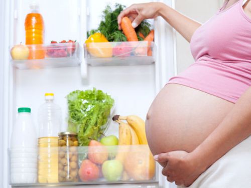 Беременная выбирает еду в холодильнике