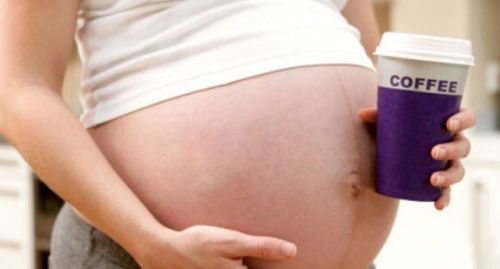 Беременная женщина держит стаканчик кофе