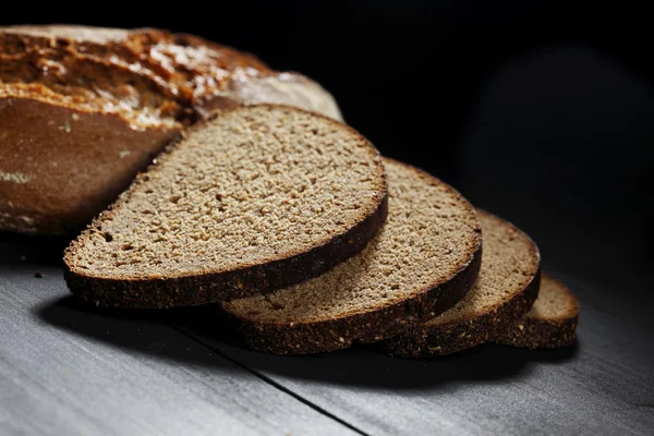 Черный хлеб нарезанный на деревянный стол — стоковое фото