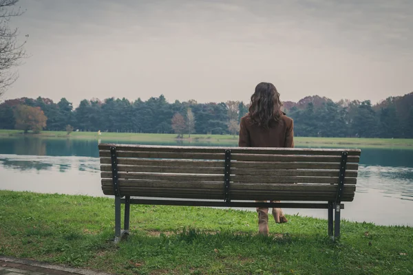Красивая молодая женщина, сидящая на скамье в городском парке — стоковое фото