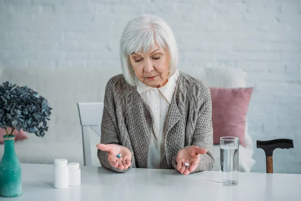 Portrait Grey Hair Woman Pills Hands Sitting Table Alone Home — стоковое фото