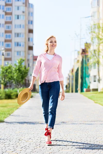 Happy Stylish Woman Holding Straw Hat Walking Street — стоковое фото