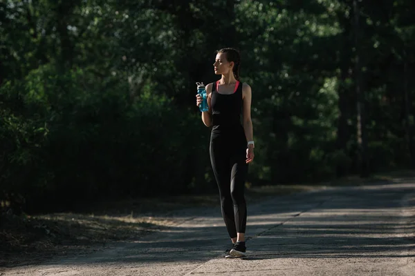 Athletic Girl Holding Sports Bottle Water Walking Park — стоковое фото