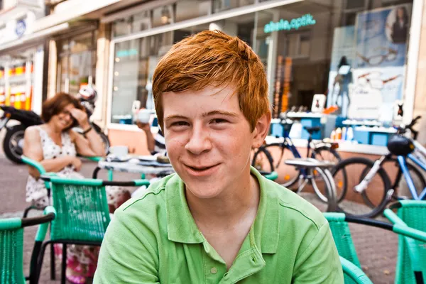 Ребенок с рыжими волосами смотрит счастливой и дружественные, сидя в o — стоковое фото